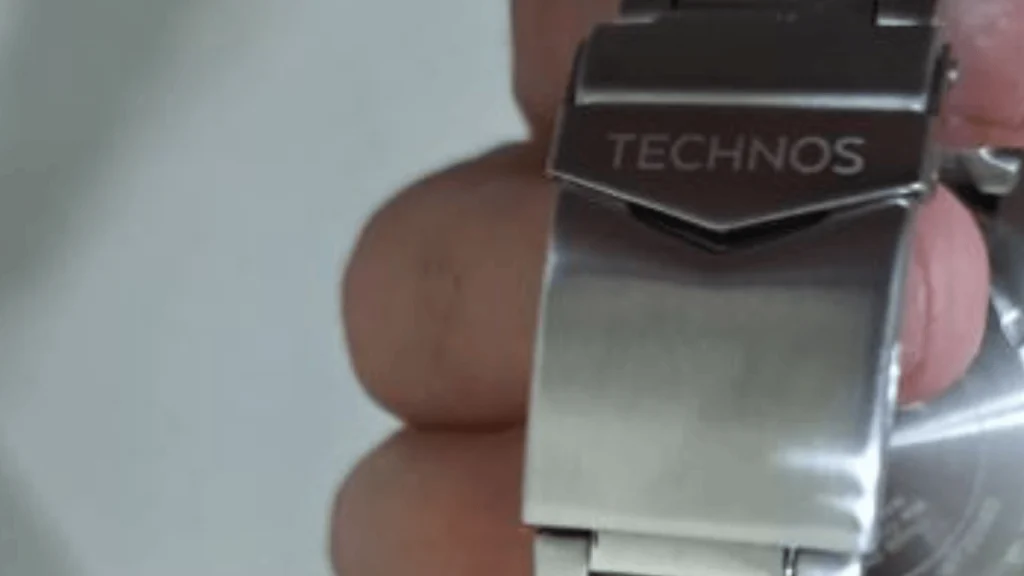 Detalhe do fecho de um relógio Technos original em aço inoxidável com logotipo gravado em baixo relevo.