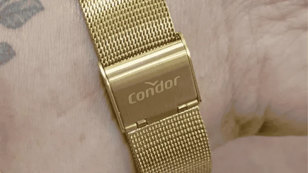 Close-up do fecho de um relógio Condor feminino dourado original com o logotipo da marca gravado no metal.