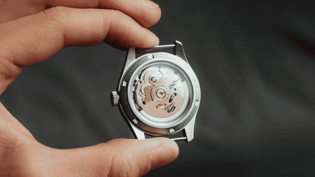 Visão detalhada do fundo de um relógio Seiko original mostrando o movimento automático, rotor gravado e acabamento técnico das engrenagens.