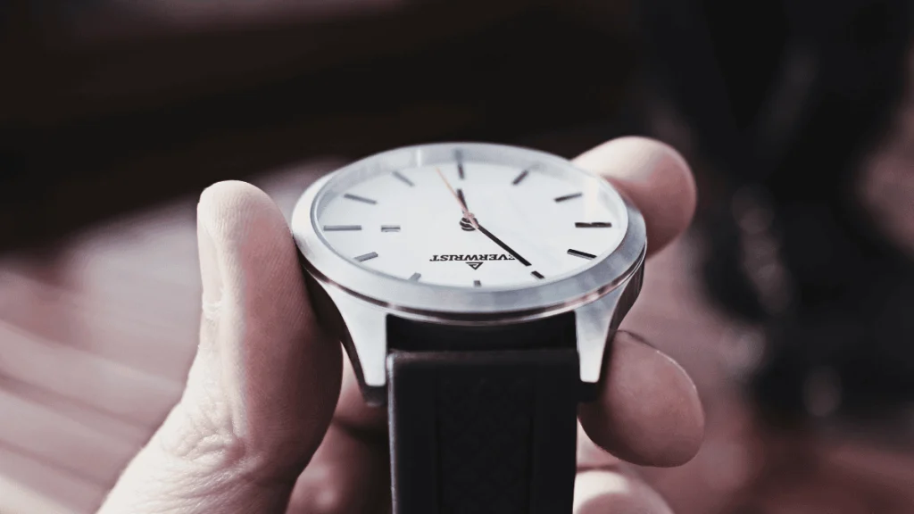 Pessoa segurando relógio de pulso lateralmente para verificar a espessura da caixa e a qualidade do acabamento do metal.