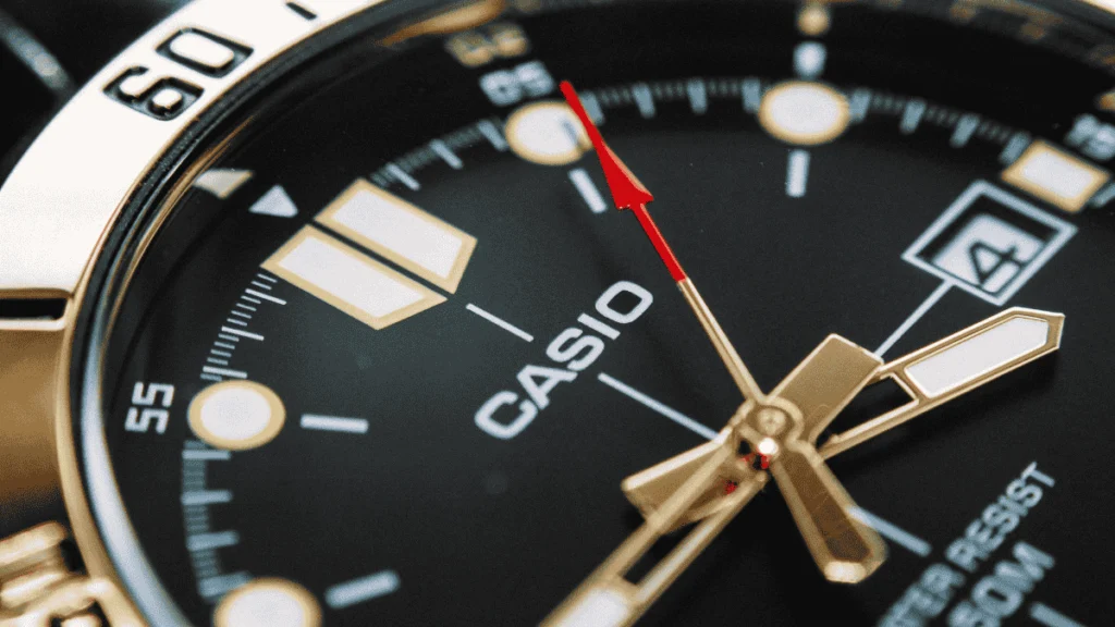 Foto macro de um relógio Casio original com foco no alinhamento do ponteiro de segundos vermelho sobre os marcadores do mostrador.